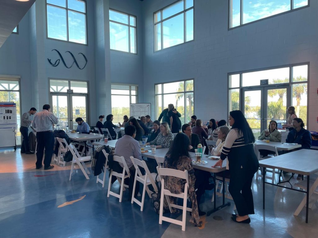 SECVBD annual meeting participants sit at tables in a bright, high‑ceilinged room, talking and eating during a break