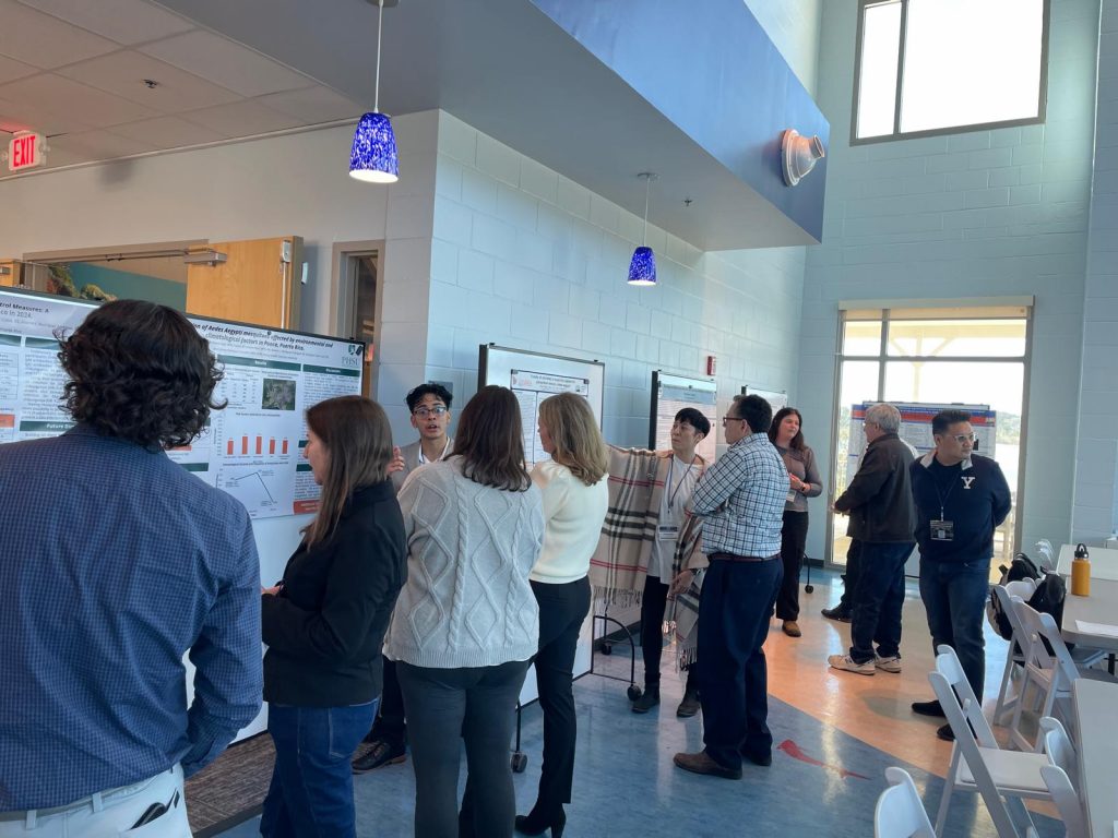 SECVBD 2025 meeting attendees gathered in a bright indoor space, viewing and discussing research posters displayed along the walls.