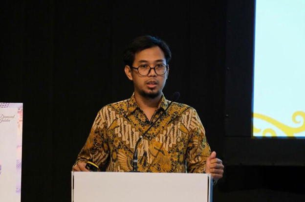 Picture of Hadian Iman Sasmita, PhD standing behind a podium on a stage, speaking into a microphone