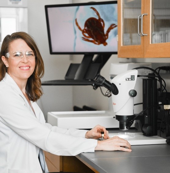 Picture of Emily Owens Pickle (M.P.H, Ph.D.) observing a tick under the microscope in the lab