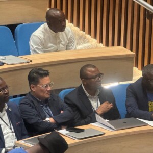 Dr. Rhoel Dinglasan in a One Health Genomics Symposium in Nigeria in 2024. Next to three collaborators, left to right: Dr. Placide Mbala (DRC), Dr. Charles Wondji (CAMEROON) and Dr. Christian Happi (NIGERIA). Five people seated at a wooden table looking on attentively during a professional conference or presentation.